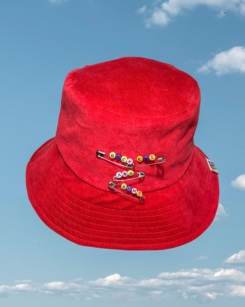 Red Safety Pin Corduroy Bucket Hat. Safety pins have colourful letter beads on which spell out Buckets & Bums