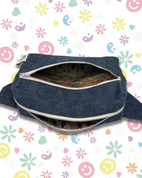 A dark blue denim pouch with an open silver zipper, showing a colorful paisley-patterned fabric lining. The lining is vintage Liberty fabric.