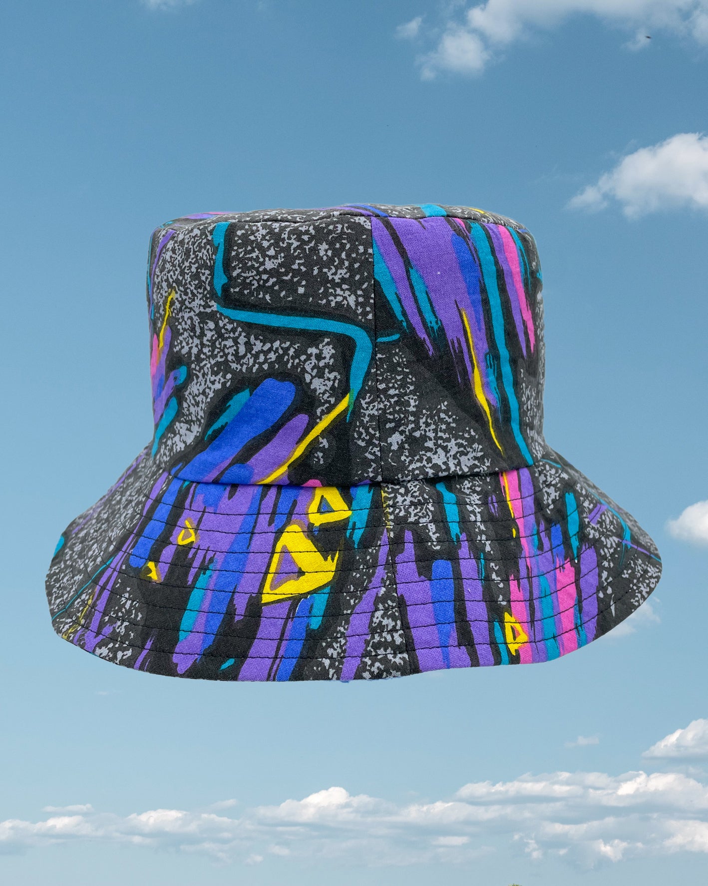 Product shot - black 80s retro bucket hat with streaks of purple, blue and pink all over
