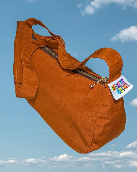 Brown silky mini shoulder bag. Close up of Buckets & Bums woven label