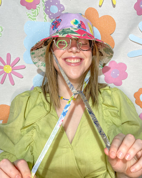 Young woman wearing the fantastic floral mismatched bucket hat, smiling and tying the drawstring